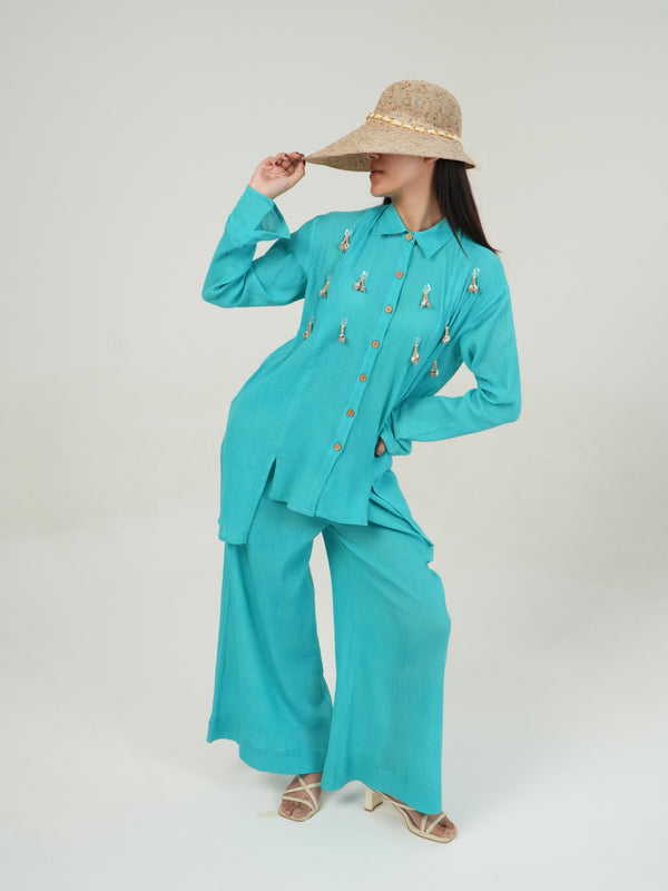 Woman wearing the Vanshitaaz Turquoise crinkled cotton co-ord — a structured button-down shirt with loose flowing pants