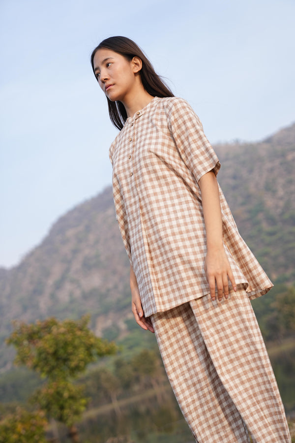 Woman wearing the Sutra Check Mandarin co-ord — a short-sleeve checked cotton tunic with straight-fit pants