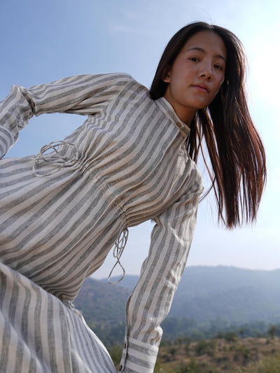 Woman wearing the Sutra Stripe Maxi Dress — a full-length striped cotton dress with a high neck and long sleeves