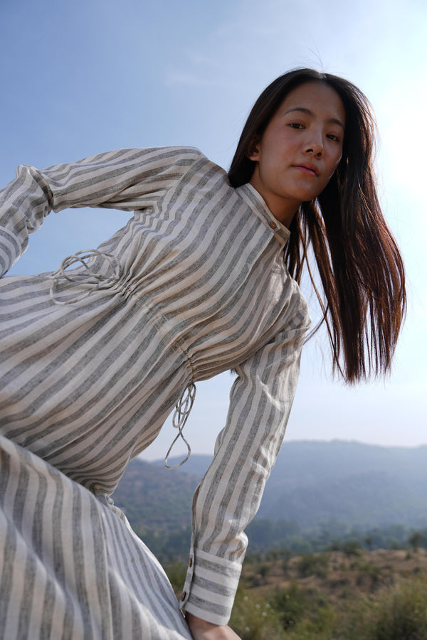 Woman wearing the Sutra Stripe Maxi Dress — a full-length striped cotton dress with a high neck and long sleeves