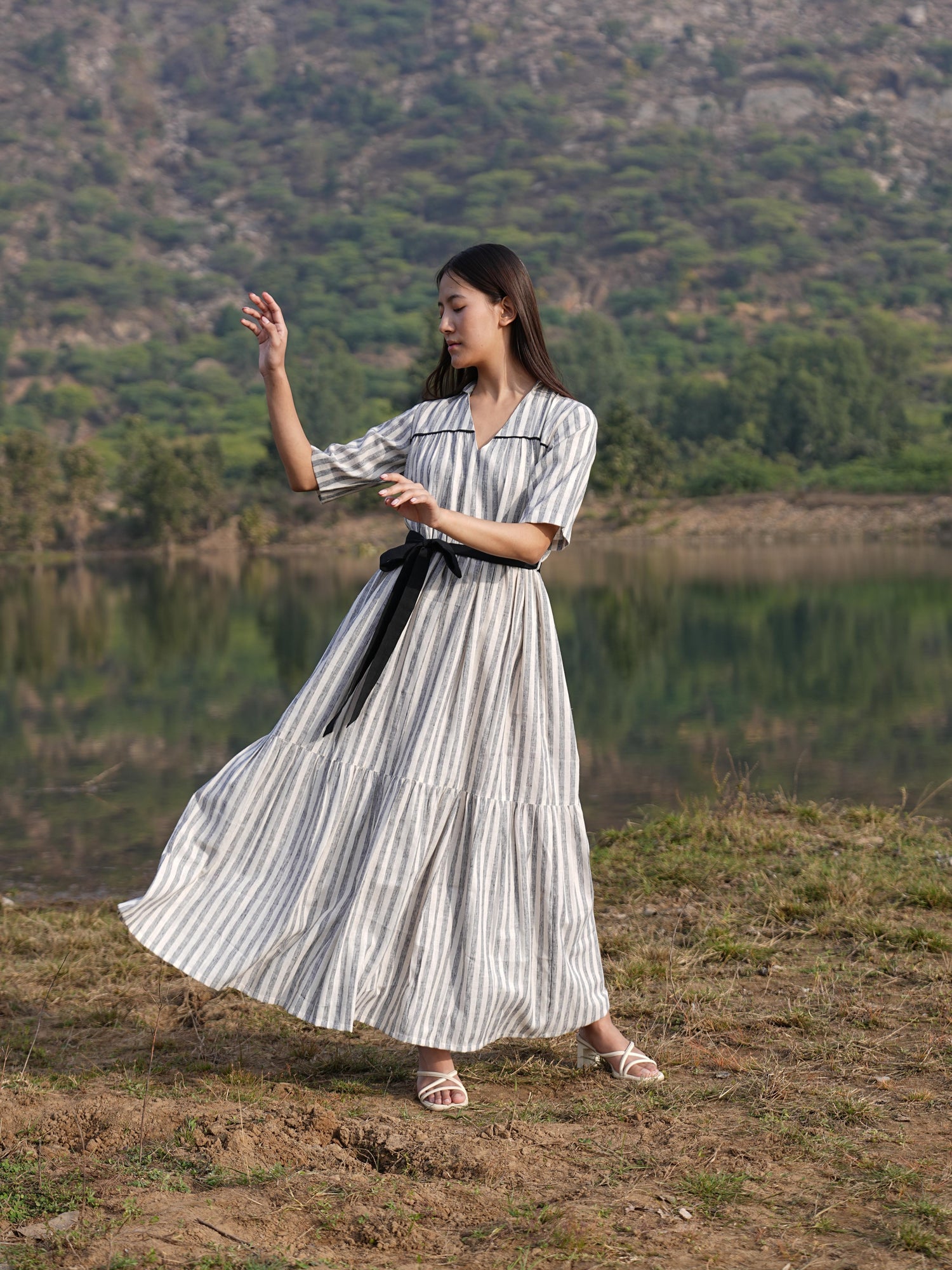 Woman wearing the Sutra Midi Stripe Dress — a striped cotton midi dress with a tiered, flared skirt
